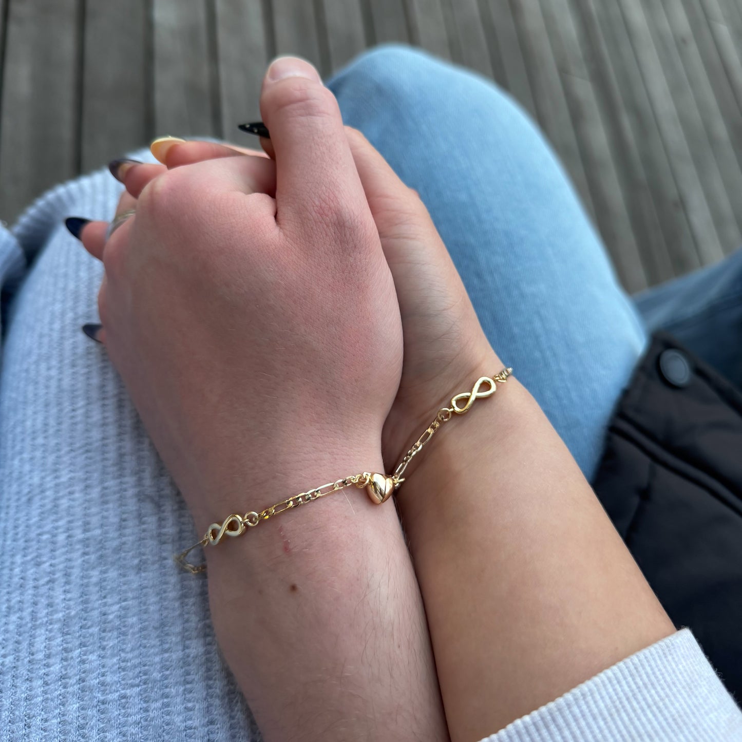Hand wearing a gold bracelet on a wooden surface