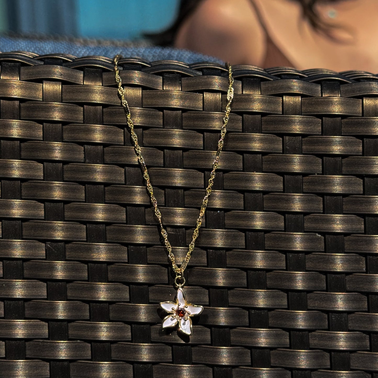 Gold necklace with a floral pendant on a textured surface