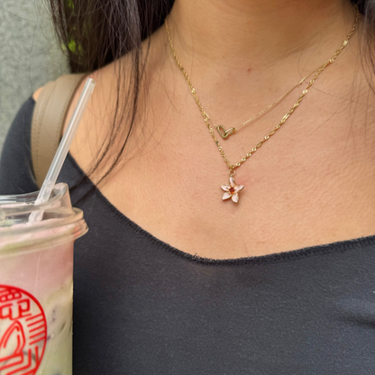 Person holding a drink with a flower necklace